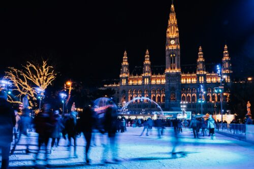 Historic building at night illuminated with lights and an icescating place in front